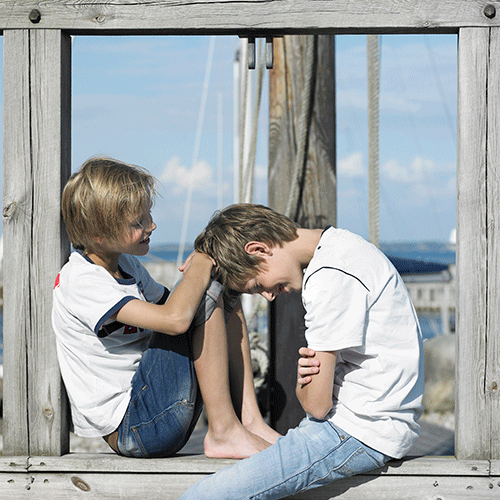 Two boys sitting in windowsill